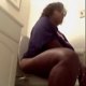 A big black woman takes a shit while sitting on a toilet. She is seen spraying deodorant into the air, reacting to her own smell, then wiping her ass. No poop is seen. About 7.5 minutes.